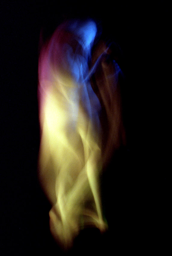 photo couleurs saturées d'un corps en mouvement laissant deviner des membres et une tête squelettique dans un nuage de lumière allant du bleu au jaune en passant par le pourpre