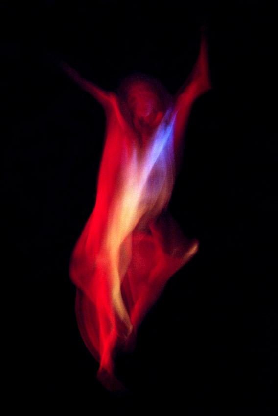 photo couleurs saturées d'un corps d'homme en mouvement dansant comme une flamme laissant deviner une tête et des bras levés le tout dans les tons rouge jaune et bleu